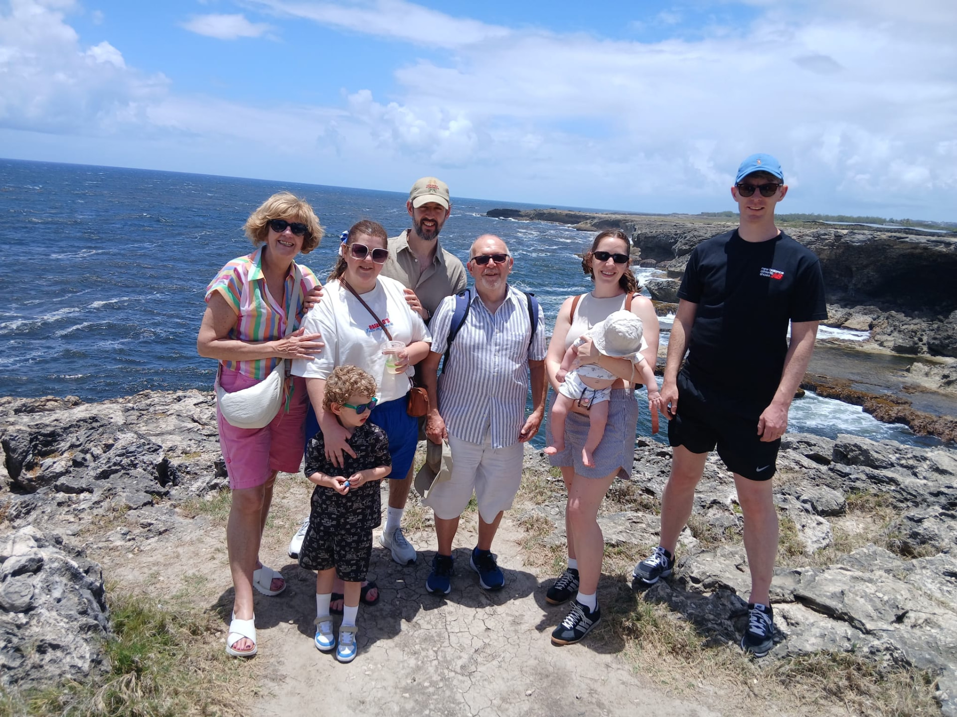 Family posing on the cliffs at River Bay during a Barbados island tour with On The House Taxi Service