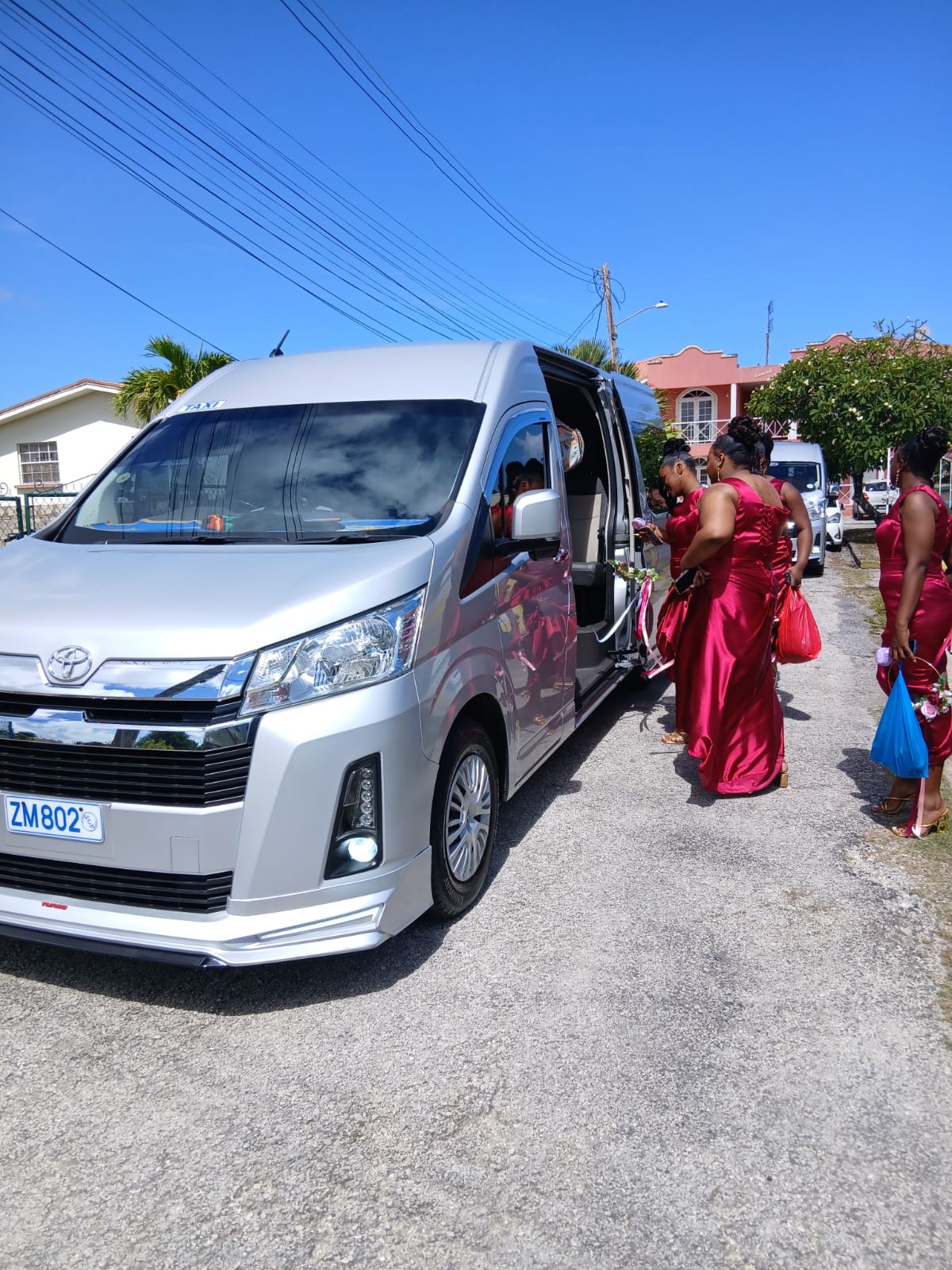 Bridesmaids in red dresses boarding the On The House Taxi Service van for a Barbados wedding