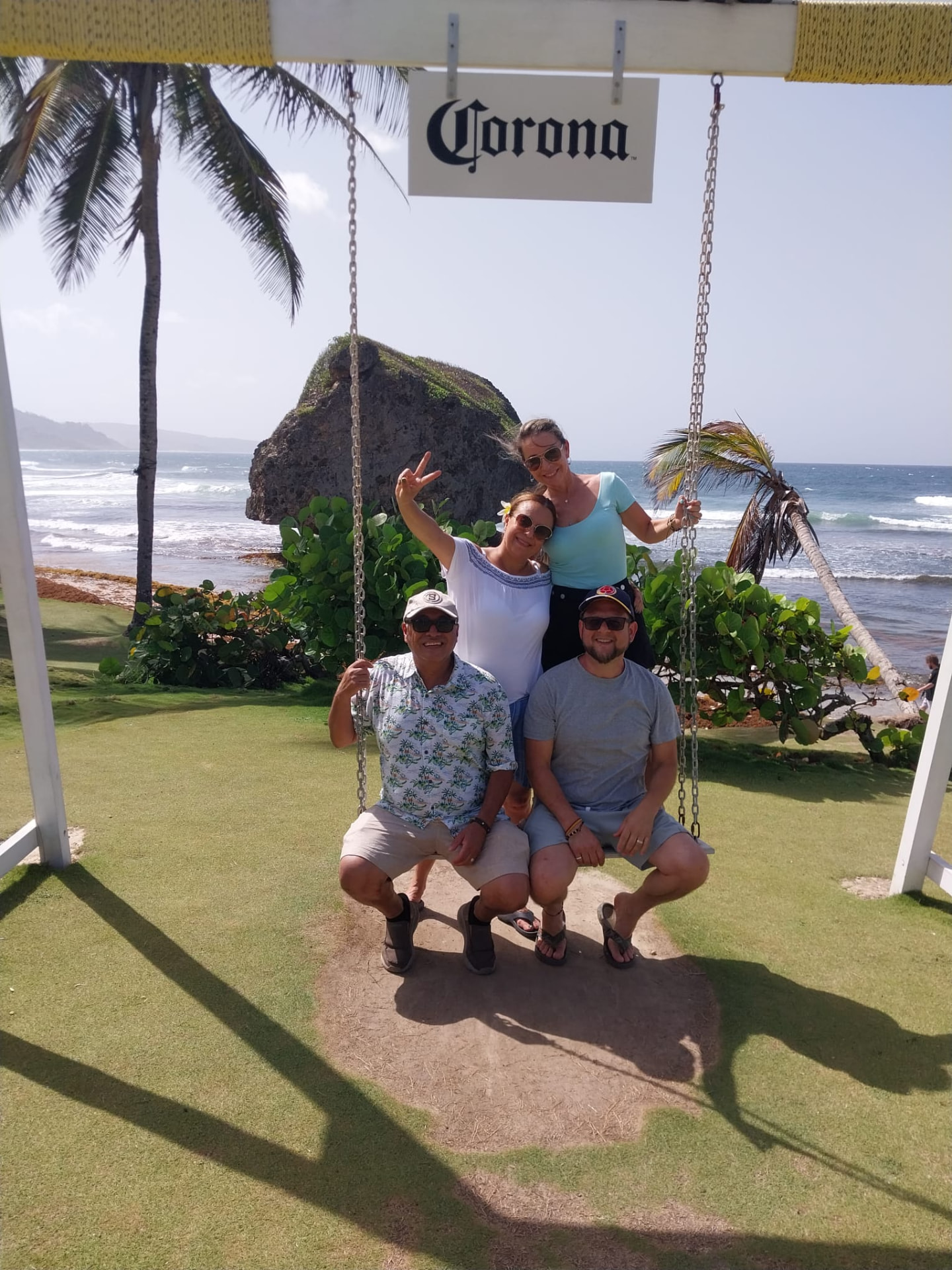 Guests on a beach swing in front of the Bathsheba rock on the east coast of Barbados during an island tour