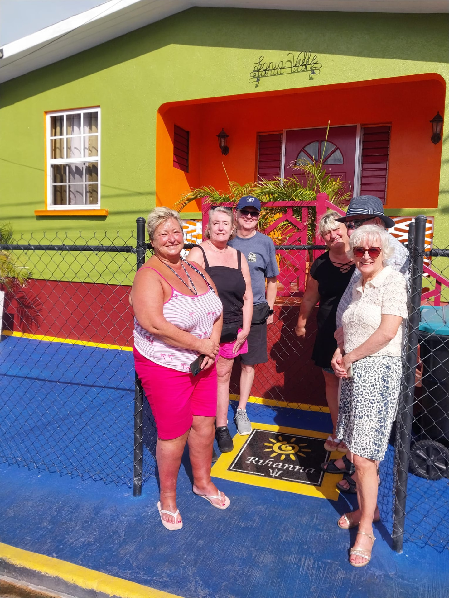 Guests posing outside Rihanna's childhood home on Rihanna Drive in Bridgetown, Barbados