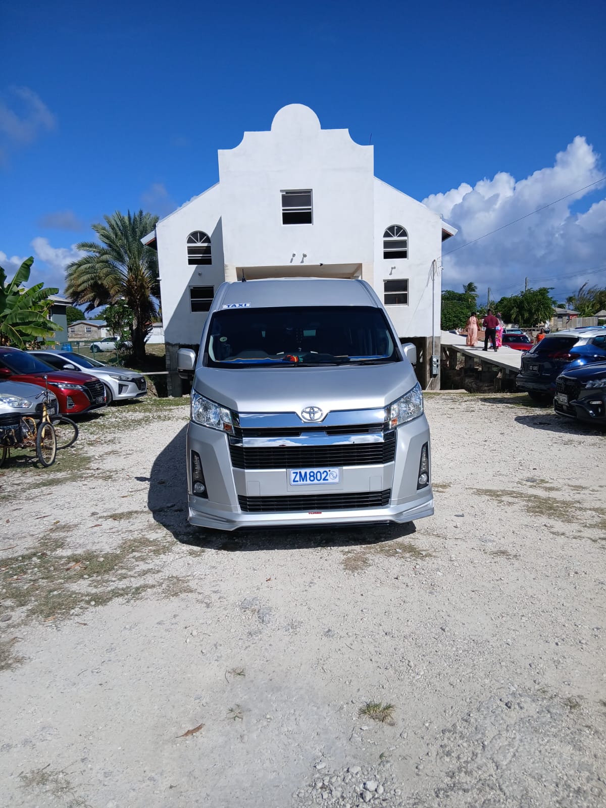 On The House Taxi Service 13-passenger luxury van parked outside a Barbados church for a wedding pickup