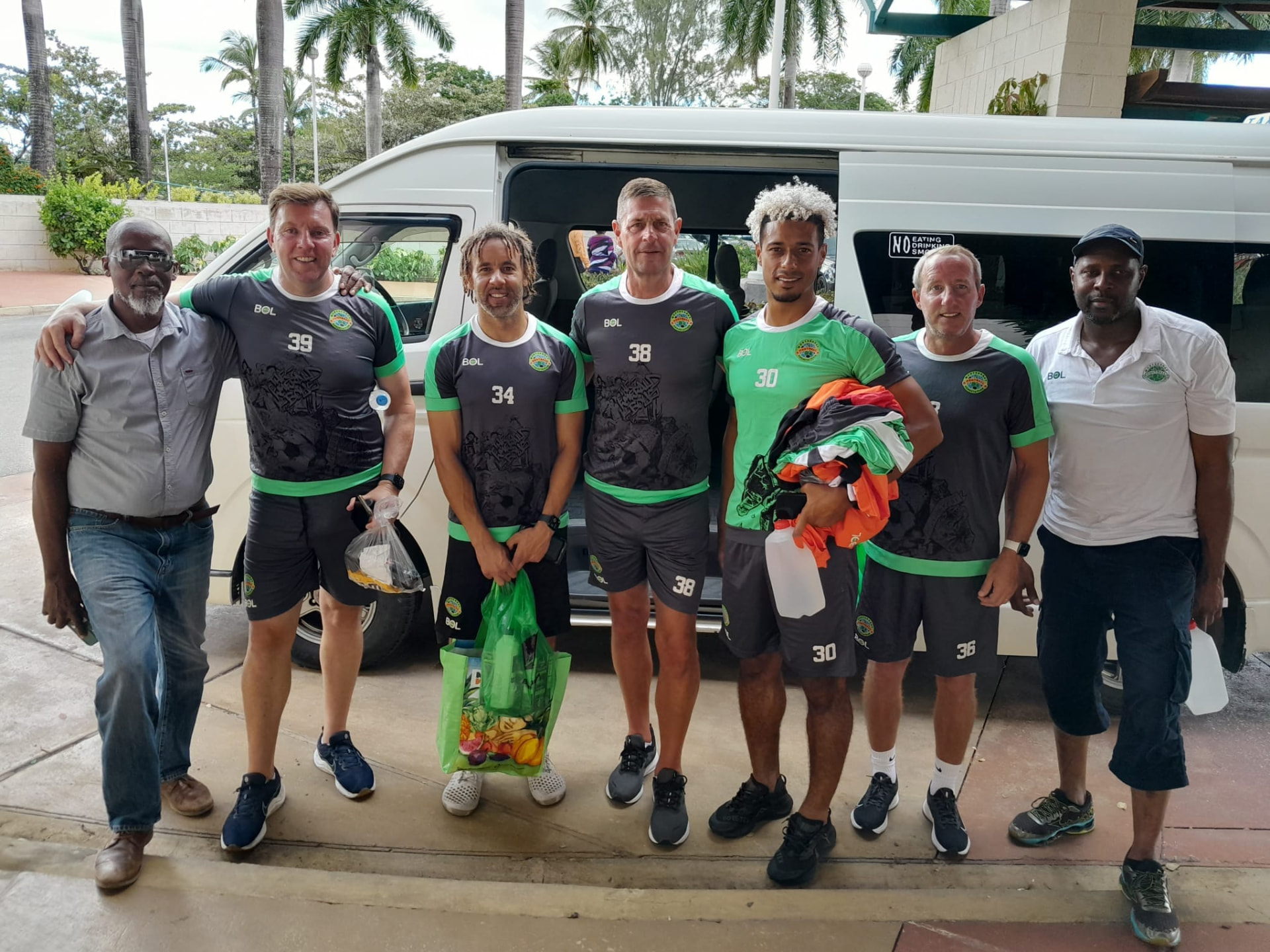 Visiting sports team beside the On The House Taxi Service 13-seat luxury van in Barbados