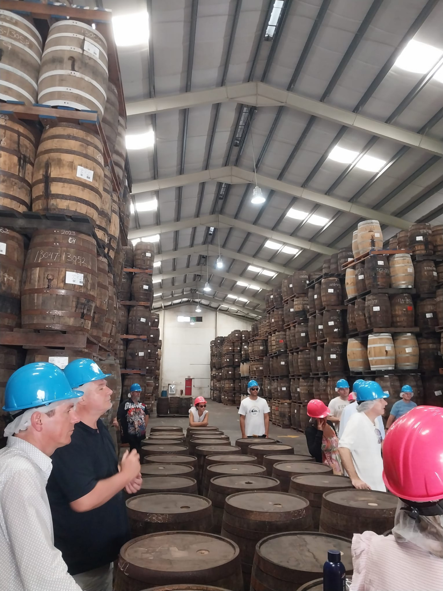 Guests in hard hats listening to the guide among ageing rum barrels on a Mount Gay rum tour in Barbados