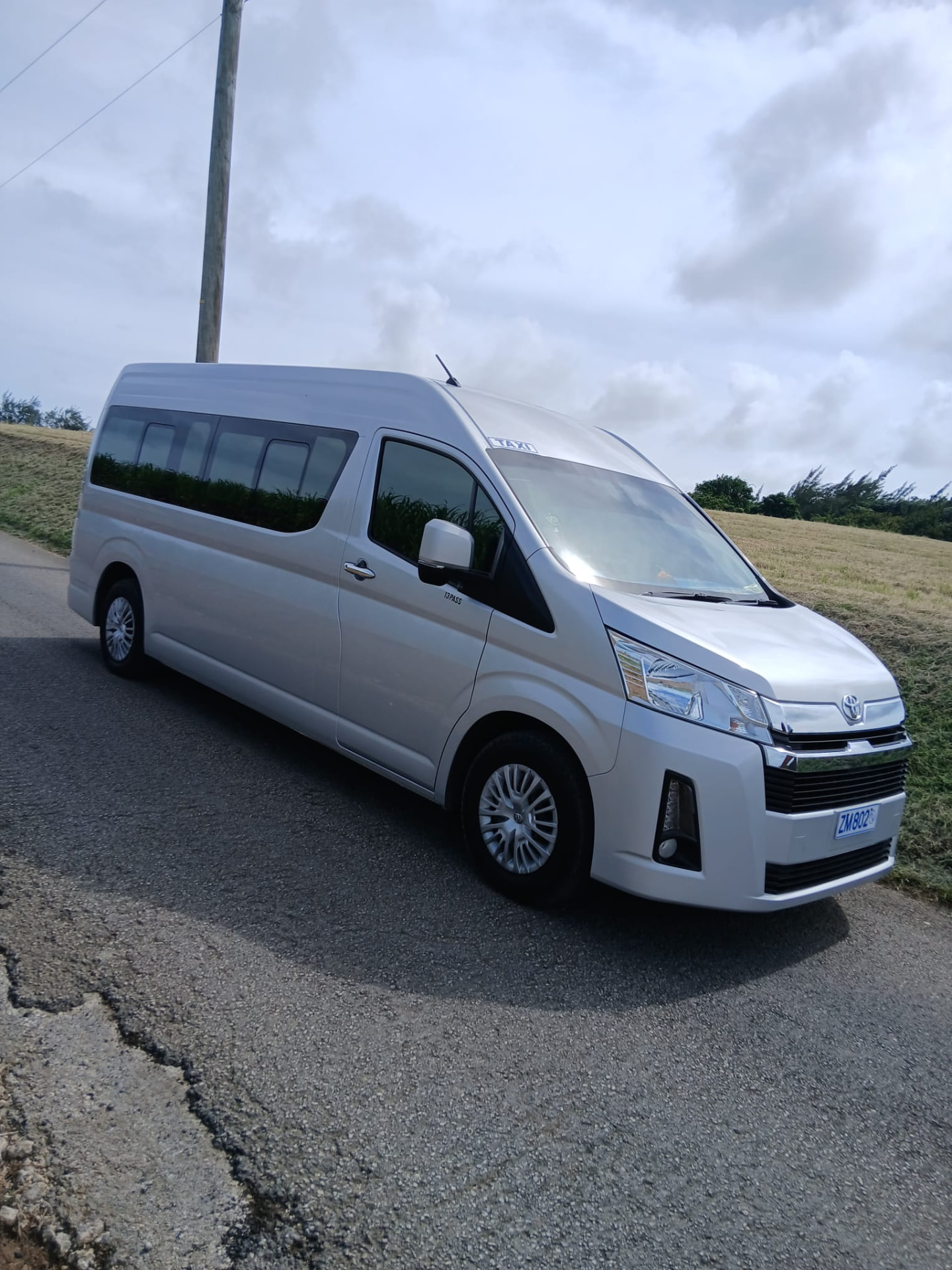 On The House Taxi Service 13-passenger luxury van on a Barbados country road ready for large family transportation