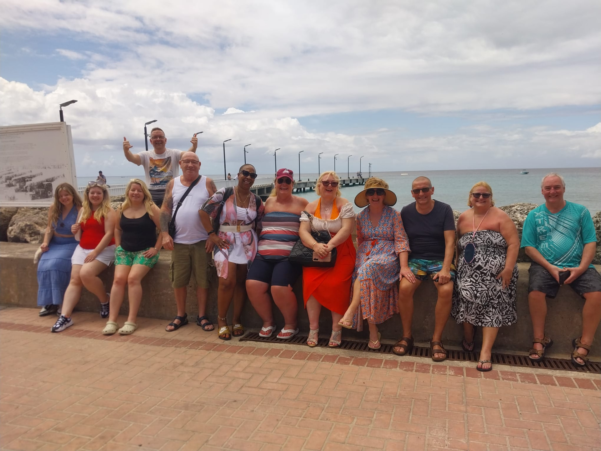 Large tour group of twelve visitors relaxing on the Speightstown sea wall during a Barbados group transfer