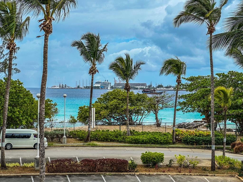 Palm-lined Barbados beach with a cruise ship anchored offshore, a short cruise port transfer from Bridgetown